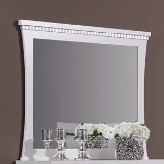 Espelho com moldura branca e cornija decorativa, refletindo velas prateadas e flores brancas