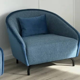 Poltrona Leonor azul com assento amplo, almofada e pernas metálicas pretas