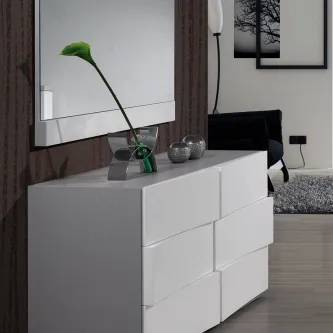 Cómoda branca com seis gavetas e espelho, vaso com flor verde e objetos decorativos