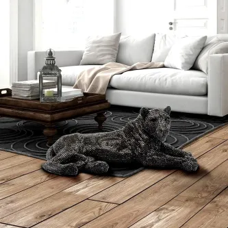 Figura leona escultura de leoa reclinada preta sobre tapete junto a mesa de centro