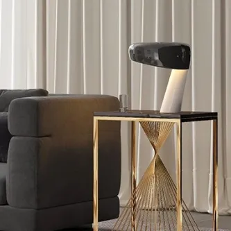 Mesa de apoio Cyclone dourada com detalhe em ampulheta, tampo negro e candeeiro