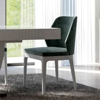 Cadeira Mondego verde-escura estofada com pernas brancas junto a mesa