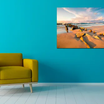 Pintura de praia de areia fina pendurada em parede azul acima de sofá amarelo