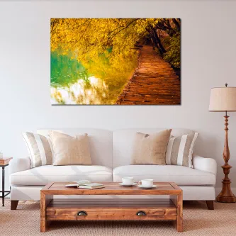 Pintura com passadiço de madeira junto a lago verde rodeado de árvores outonais