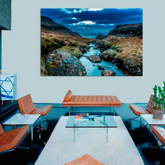 Pintura de paisagem rochosa com ribeiro entre pedras e montanhas sob céu azul