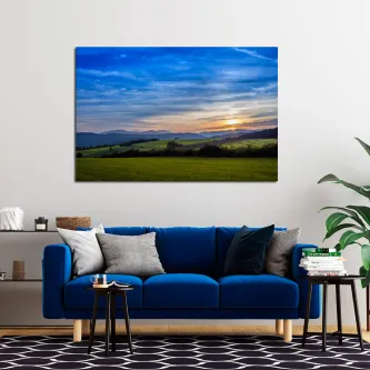 Pintura de paisagem de prados com colinas verdes e pôr do sol, pendurada acima de sofá azul