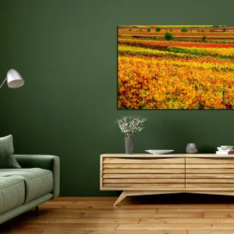 Pintura de paisagem colorida com campos floridos amarelos e laranjas numa parede verde