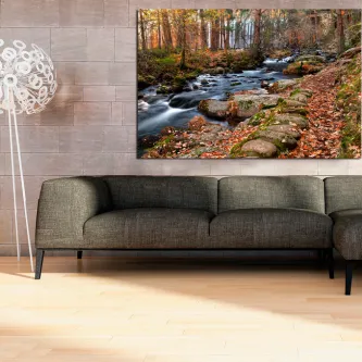 Pintura de riacho montanhoso em floresta outonal, pendurada sobre sofá cinzento