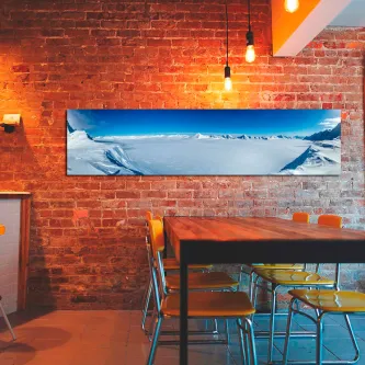 Pintura de paisagem ártica panorâmica pendurada em parede de tijolo acima de mesa