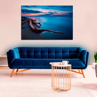 Pintura de praia com toras pendurada acima de sofá azul