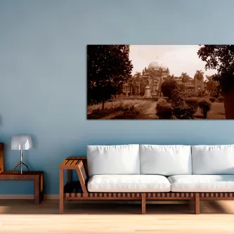 Sofá sob pintura de paisagem da Índia em sépia numa parede azul
