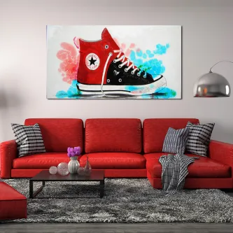 Caixa de botas juvenil com desenho de ténis vermelho e preto em quadro sobre sofá vermelho