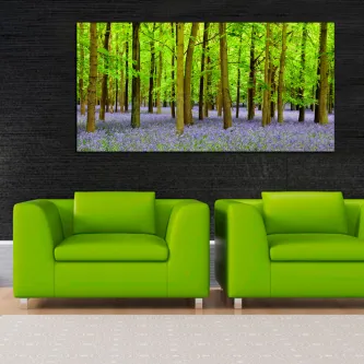 Pintura de bosque verde com tapete de flores azuis sobre dois sofás verdes