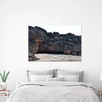 Pintura de paisagem de rochas pendurada sobre cama branca com almofadas