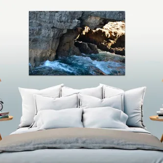Cama dupla com quadro pintura de paisagem rochosa mostrando mar a bater numa gruta rochosa