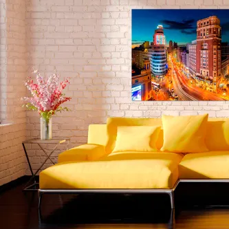 Sofá amarelo junto a quadro da Gran Vía de Madrid iluminada à noite