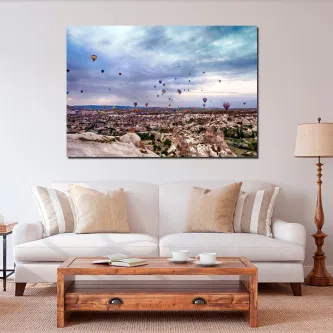Pintura da Capadócia com balões sobre paisagem rochosa, pendurada numa sala com sofá.