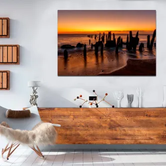 Quadro de pôr do sol na praia pendurado sobre aparador de madeira