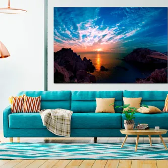 Quadro de nascer do sol sobre mar e rochedos pendurado acima de sofá