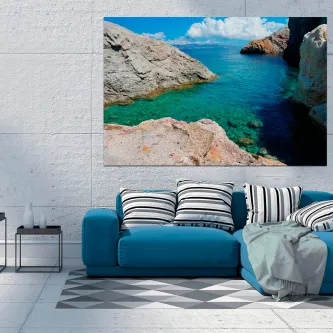 Pintura de paisagem marítima com enseada rochosa e água turquesa sobre sofá azul