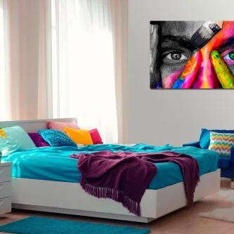 Quarto com cama turquesa e quadro de rosto pintado de menina com mãos coloridas