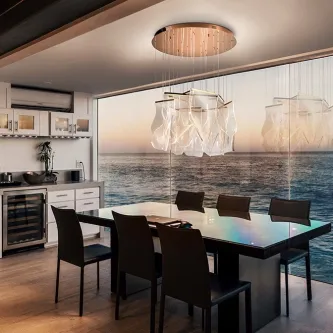 Candeeiro de teto Velos com placas translúcidas sobre mesa de jantar e vista para o mar