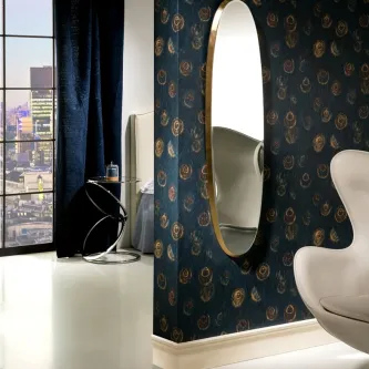 Espelho Aries Oval com moldura dourada pendurado em parede azul estampada