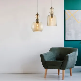 Candeeiro de teto tone bronze com dois pendentes de vidro âmbar sobre poltrona verde