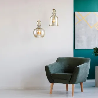 Candeeiro de teto Tone Bronze com dois globos de vidro sobre poltrona verde
