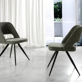 Cadeira Senses cinzenta estofada com pernas pretas inclinadas em chão de mármore
