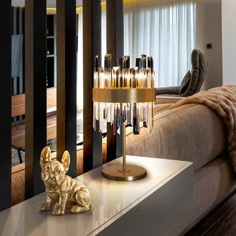 Candeeiro de mesa Grace dourado com pendentes de cristal sobre consola junto a estatueta de cão