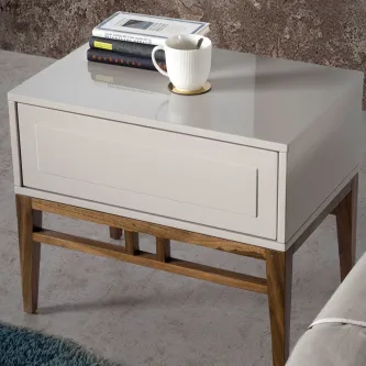 Mesa de cabeceira Arezzo cinzenta com gaveta e pés em madeira, livros e caneca