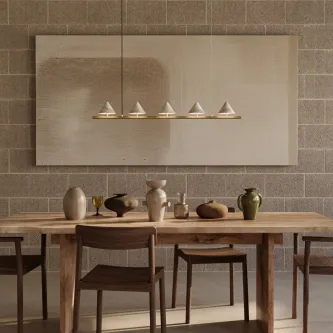 Candeeiro suspenso Anza com barra horizontal e cinco cúpulas cónicas douradas sobre mesa de madeira
