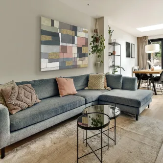 Pintura Zonas abstrata com blocos coloridos, pendurada sobre sofá cinzento numa sala