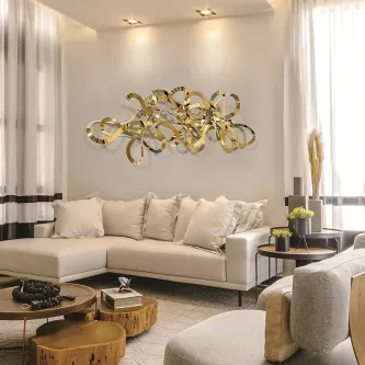 Escultura de parede Medusa dourada e abstrata acima de sofá numa sala luminosa