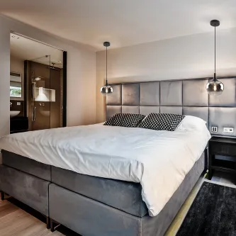 Candeeiro suspenso Opaz, dois globos de vidro fumado sobre cabeceira acolchoada