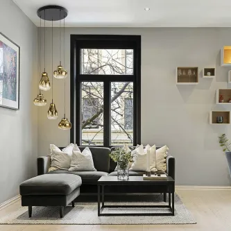 Candeeiro de teto Aledis 5L dourado com cinco pendentes sobre sofá numa sala moderna