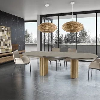 Mesa extensível Irati em madeira com tampo oval, cadeiras e candeeiros numa sala