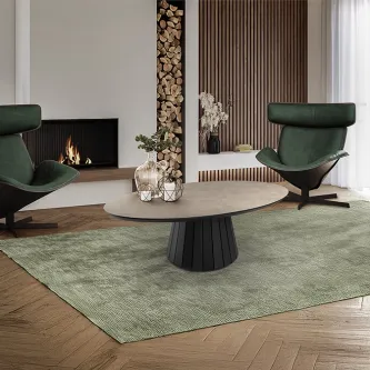 Mesa de centro Koria redonda com tampo claro e base preta canelada, sobre tapete verde