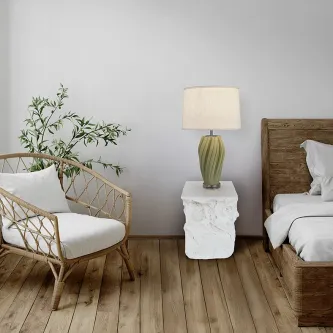 Mesa de apoio Block branco esculpido com candeeiro verde entre cama e cadeira rattan