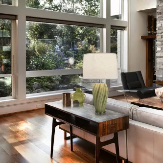 Candeeiro de mesa Salome com base verde estriada e cúpula branca numa consola de madeira