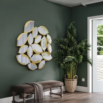 Espelho Sandal dourado com peças em forma de pétala montado numa parede verde