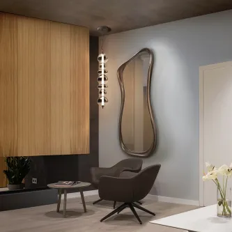 Espelho Gina de parede com moldura ondulada sobre poltrona e mesa lateral