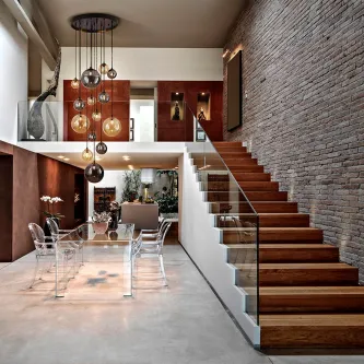 Candeeiro de teto dark grande com múltiplas esferas de vidro pendentes sobre mesa de jantar