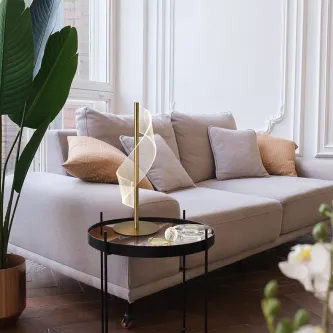 Candeeiro de mesa Velas dourado com cúpula translúcida junto a mesa e sofá