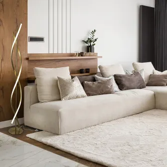 Candeeiro de pé Dido curvo ao lado de sofá bege numa sala moderna