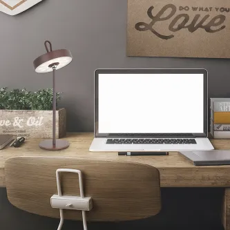 Candeeiro de mesa Gong portátil em metal sobre secretária junto a computador portátil