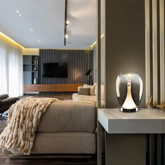 Candeeiro de mesa Suspiro moderno em vidro iluminado sobre mesa lateral numa sala