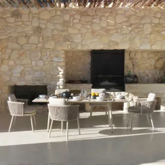 Mesa de jardim sabbia com quatro cadeiras e loiça numa esplanada junto a parede de pedra