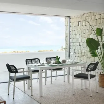 Mesa de jardim retangular Kurve branca com quatro cadeiras em varanda junto ao mar